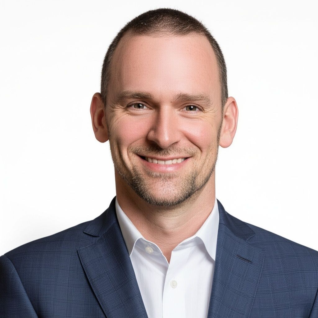 Person wearing a navy blue suit jacket and a white shirt against a plain white background.