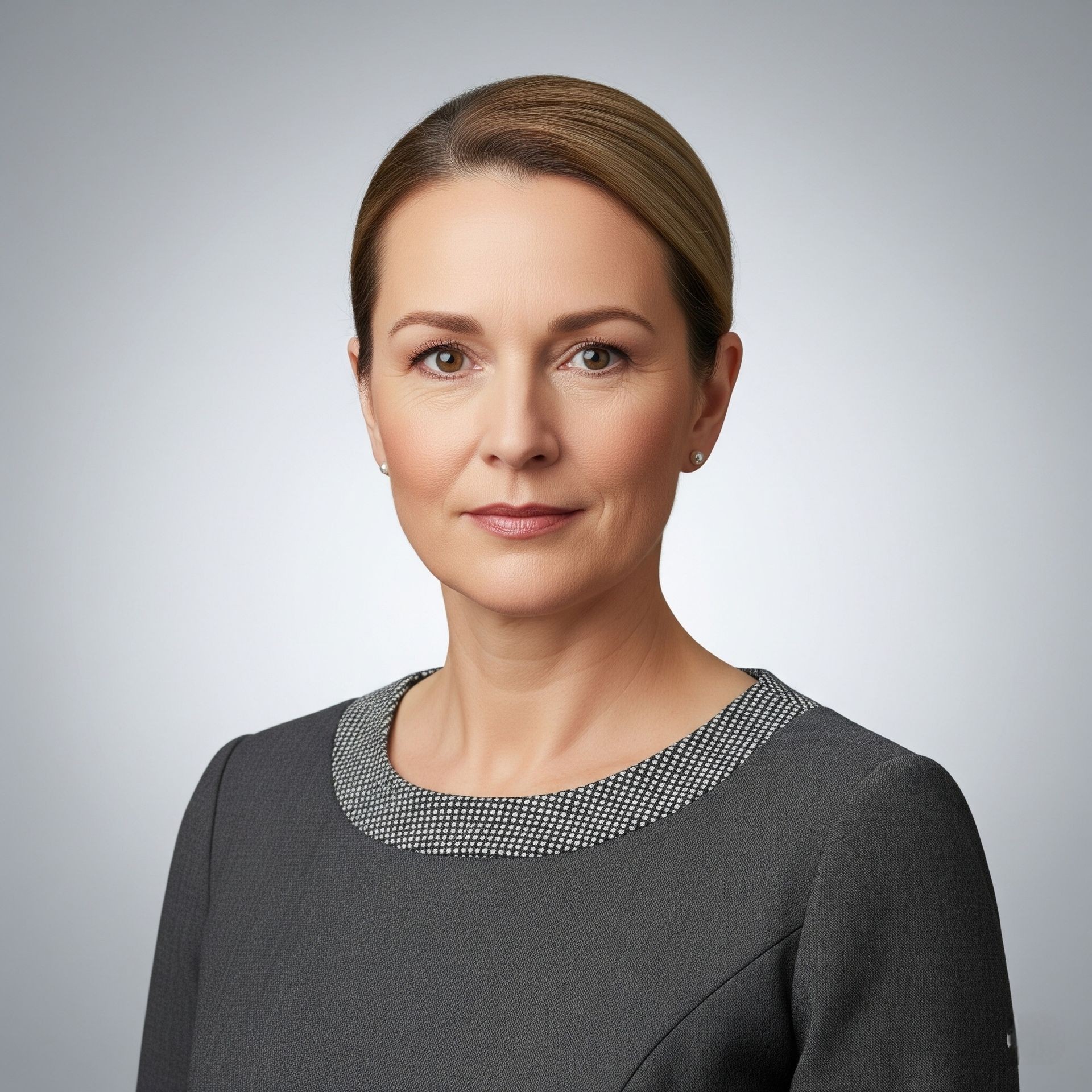 Woman wearing a dark grey dress with a beaded neckline on a neutral grey background.