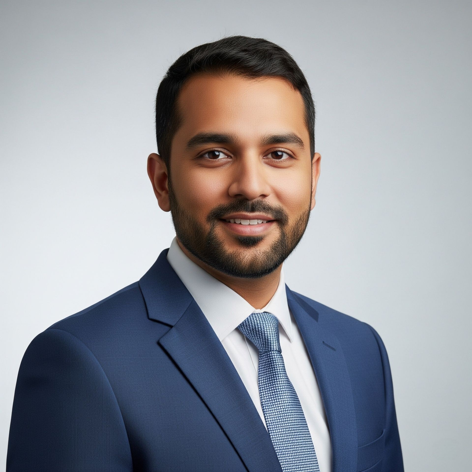 Professional portrait of a person wearing a blue suit and tie against a grey background.