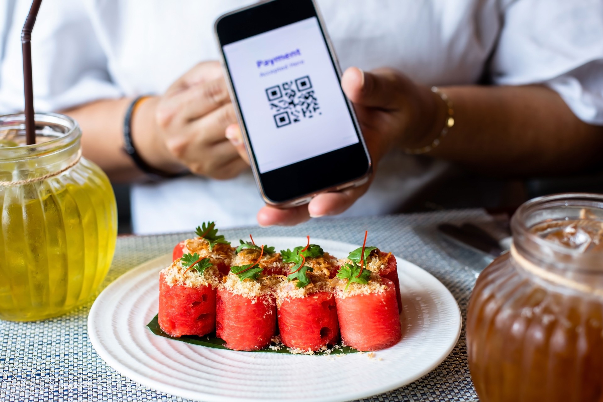 Selective focus to Thai food that uses watermelon as the main ingredient with blurry simulate QR code tag on smartphone.