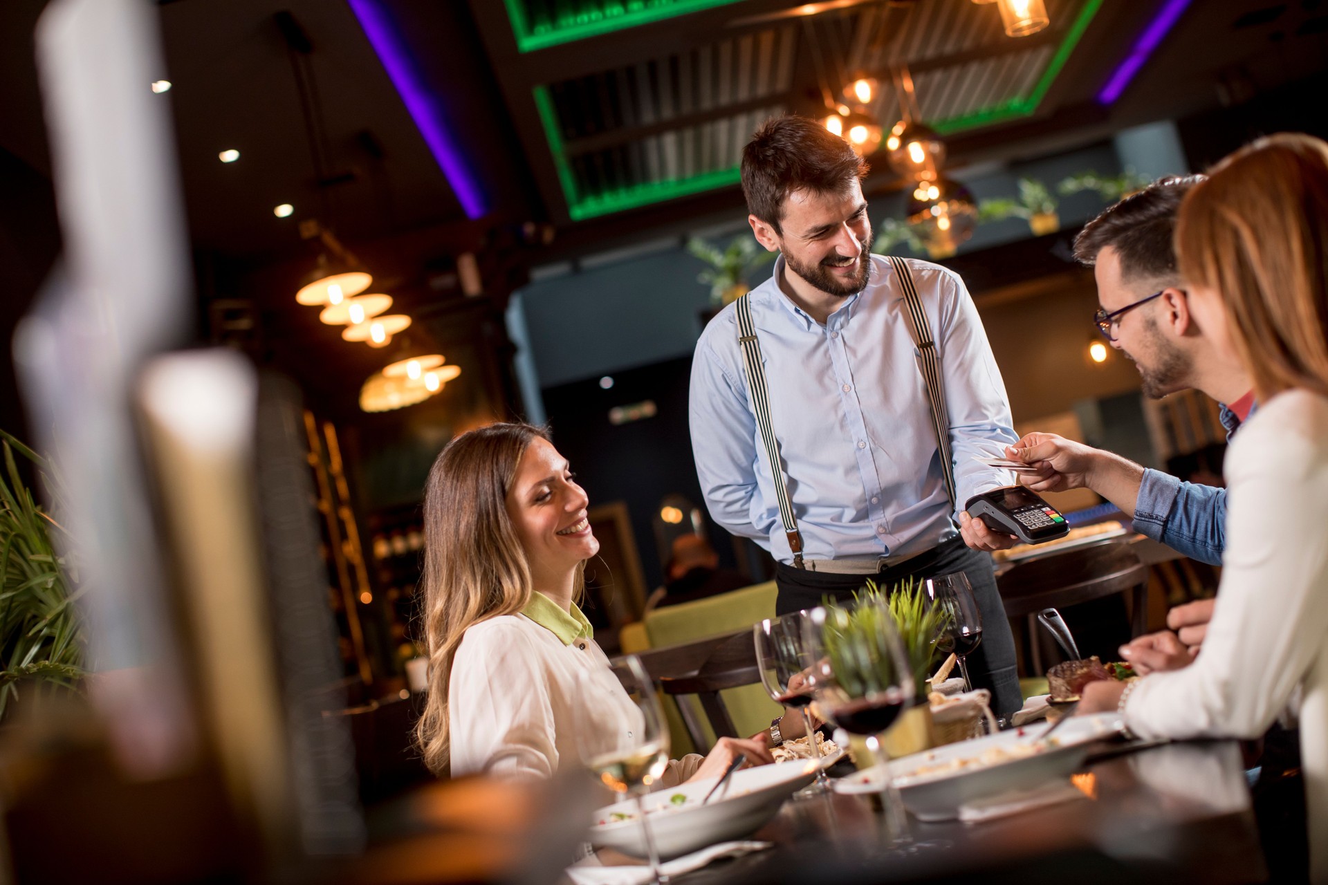 Young man paying with contactless credit card in the restaurant